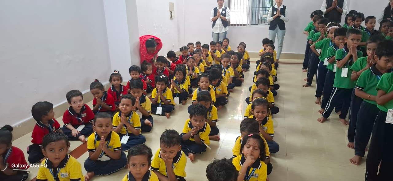 Children sitting in rows with hands folded during morning assembly