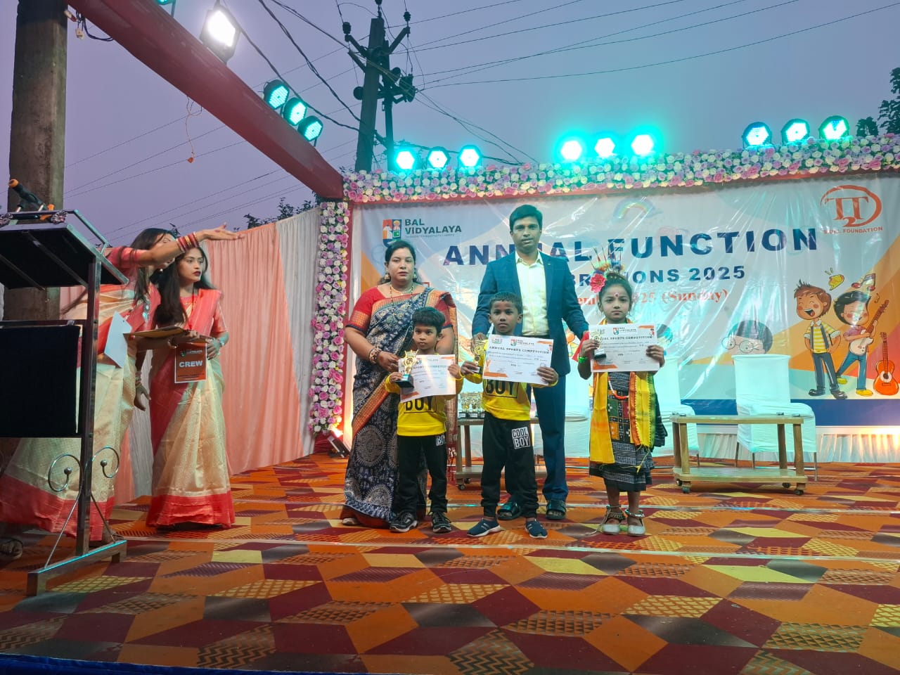 Children holding trophies and certificates on stage at Bal Vidyalaya Annual Function Celebrations 2025